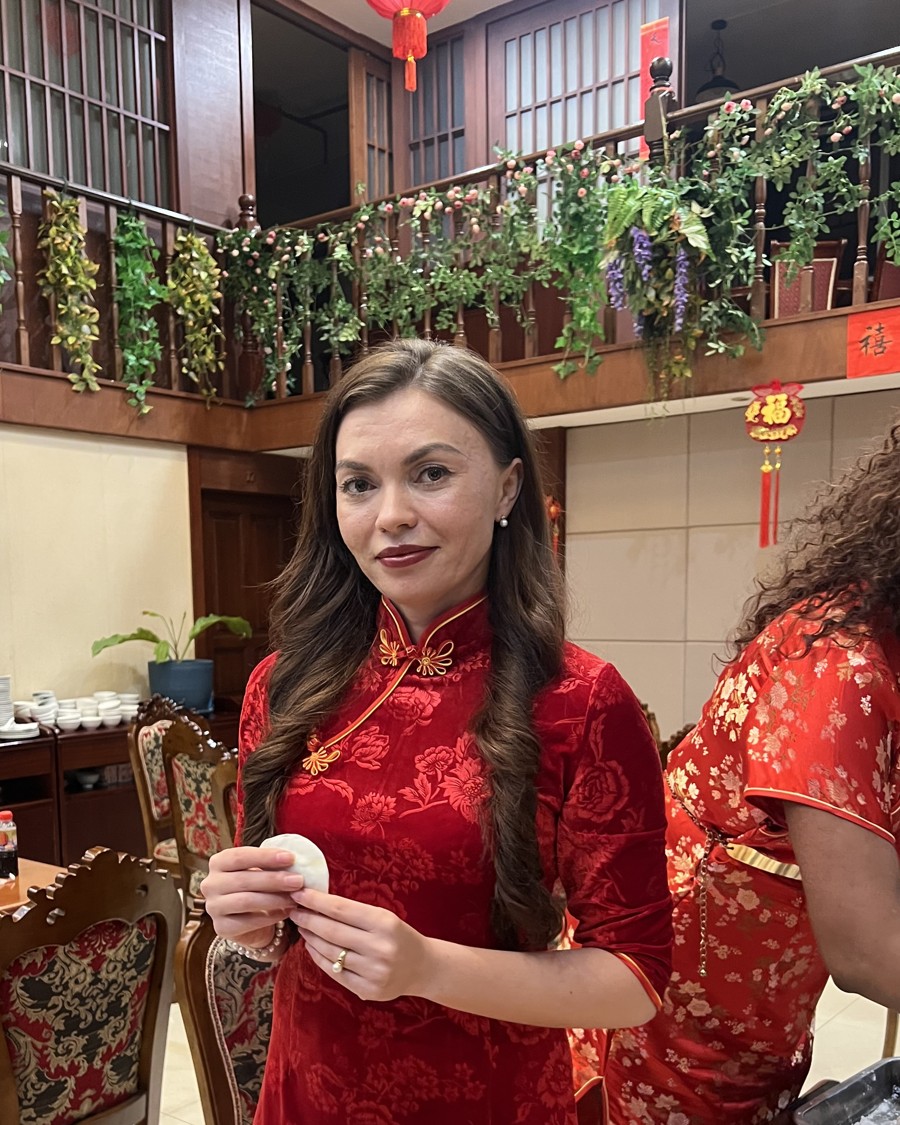 Alisa in a red qipao making dumplings